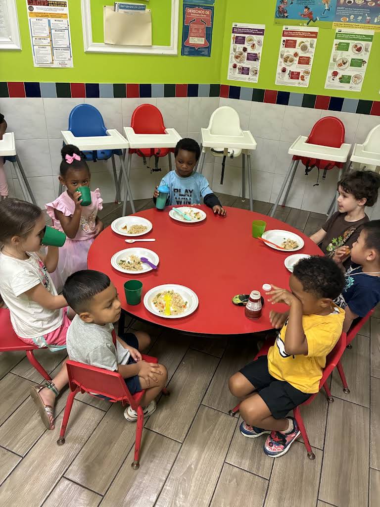 Children sharing a meal around a red round table at Bloom & Beyond